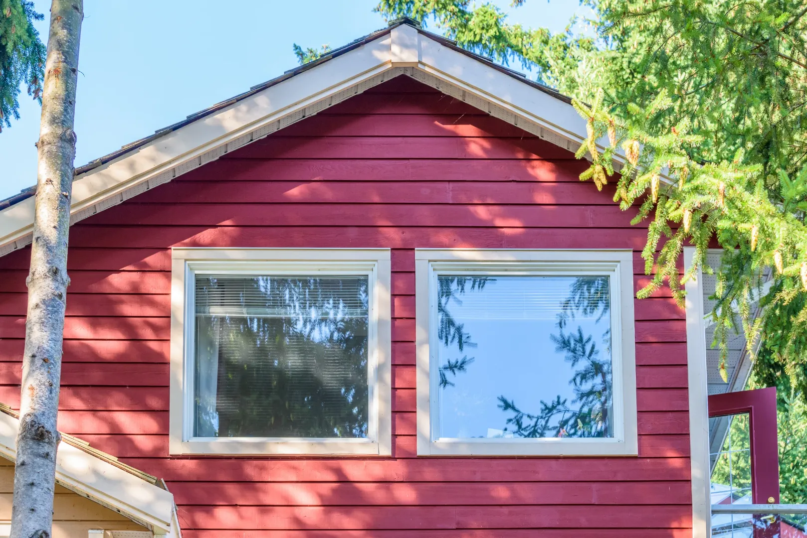 Red fiber cement siding on a house exterior with white-trimmed windows