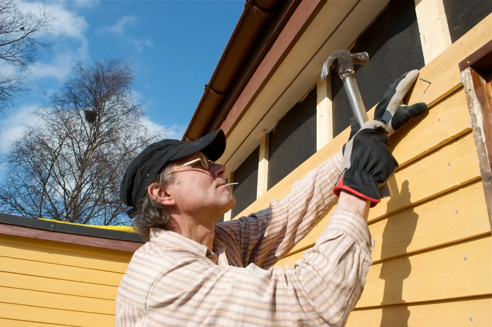 A man repairing a siding of a house