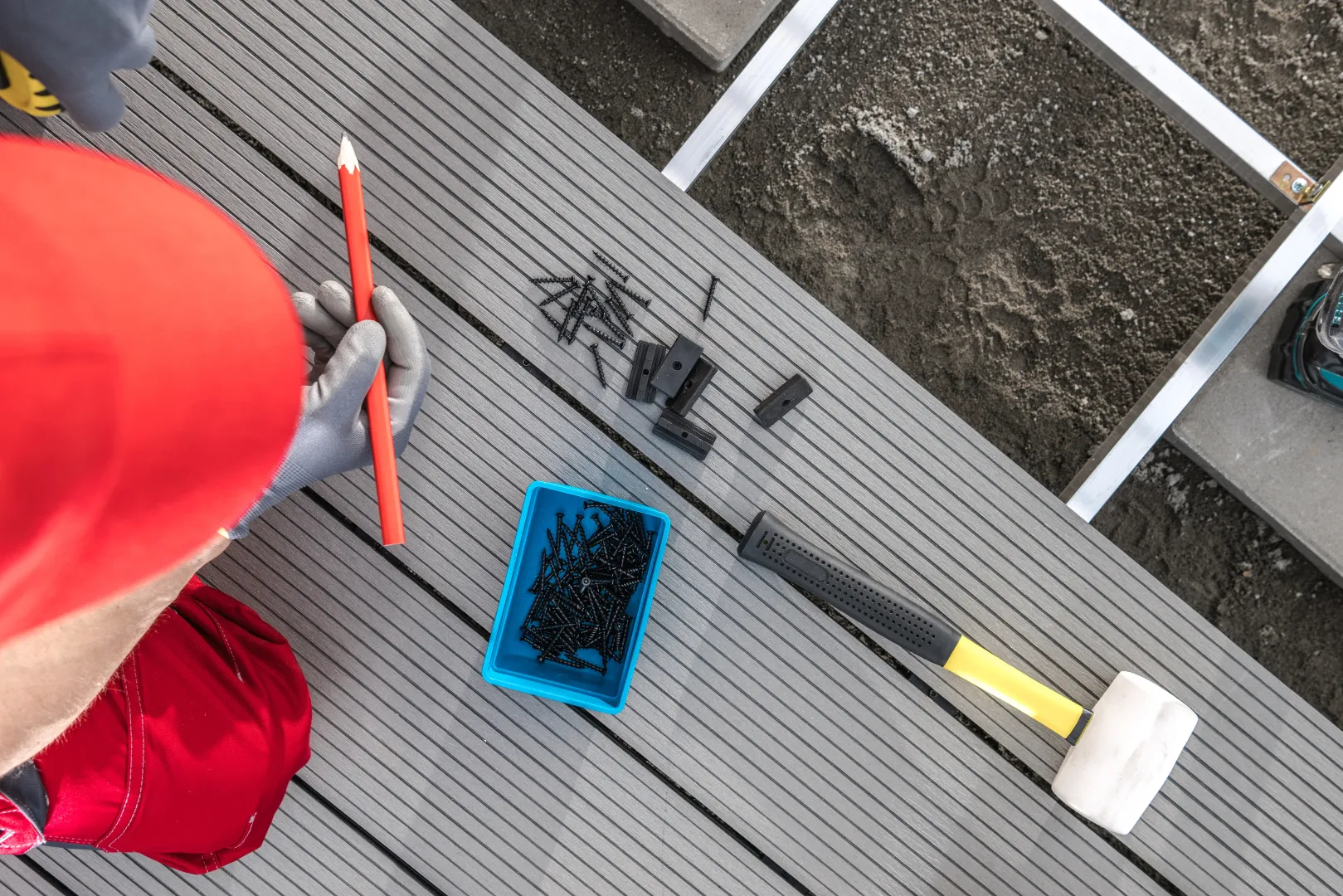 A contractor inspecting and working on composite decking boards to assess repairs and replacement needs.