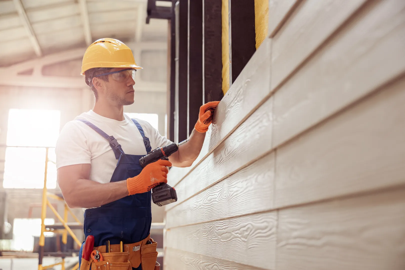 Worker installing fiber cement siding on a house exterior